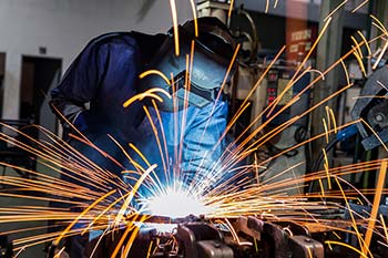 Welder in a mask and coat surrounded by sparks
