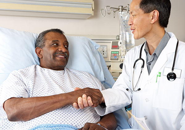man in hospital bed talking to doctor