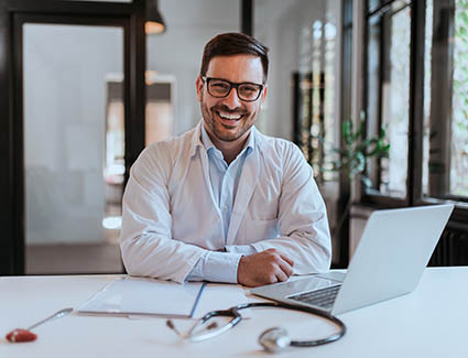 Man in a white doctor's coat sitting at a desk