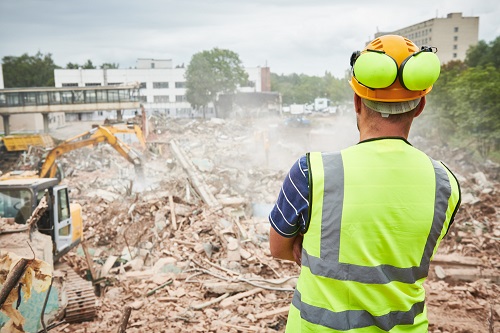 Construction worker looking at a demolished building