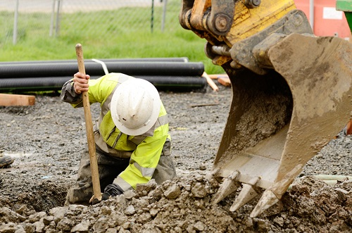Construction worker digging a hole on a utility site